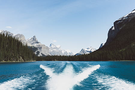body of water between snow-capped mountain and pine trees thumbnail