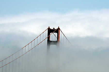 red metal bridge surrounded by white clouds during daytime thumbnail