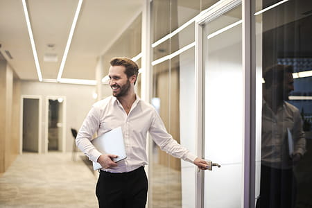 A young bearded caucasian man wearing formals entering a glass cabin thumbnail