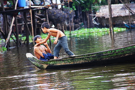 two boys on green boat on body of water thumbnail