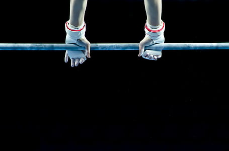 person wearing white gloves holding on gray metal bar thumbnail