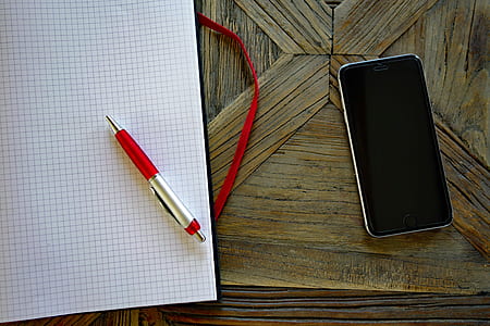 red pen beside black Android smartphone on brown surface thumbnail