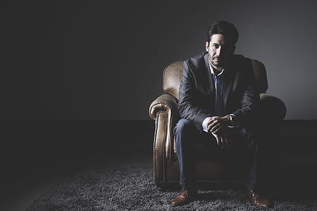 man sitting on brown cushion armchair thumbnail