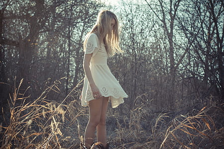 woman in white dress standing in withered forest thumbnail