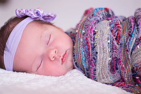 closed up photography of baby lying on white textile thumbnail