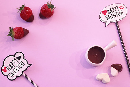 three red strawberries, white ceramic cup, and white heart mallows on pink surface thumbnail