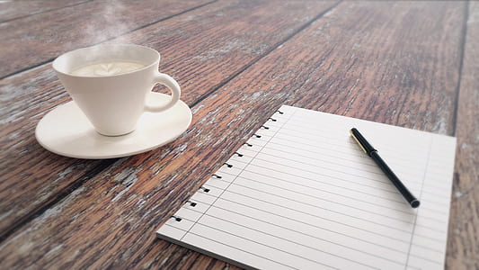 black pen on white lined printer paper near white mug filled with coffee thumbnail