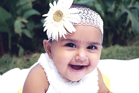 baby in white fleece sleeveless shirt wearing white daisy flower head accessory thumbnail