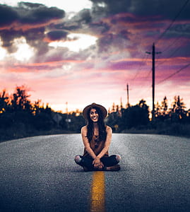 selective focus photography of woman sitting in the middle of the road thumbnail