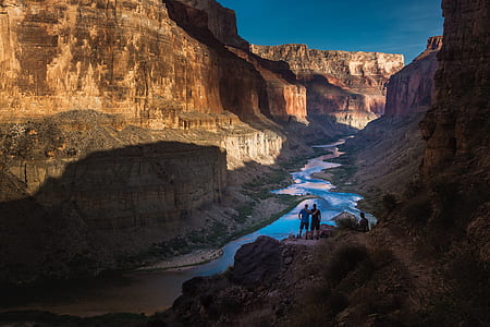 three persons standing on rock overlooking river thumbnail