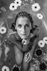 naked black haired woman taking a bath on bathtub full of flowers thumbnail