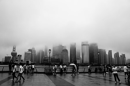 grayscale photo of group of people standing along the bay thumbnail