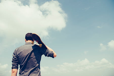 man holding skateboard during cloudy day thumbnail