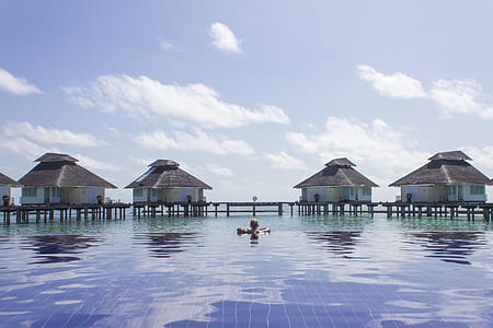 person in body of water near floating cottages thumbnail