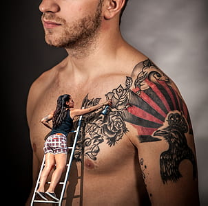 woman painting man's floral tattoo on wall thumbnail