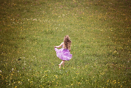 girl in purple dress standing on green grass field thumbnail
