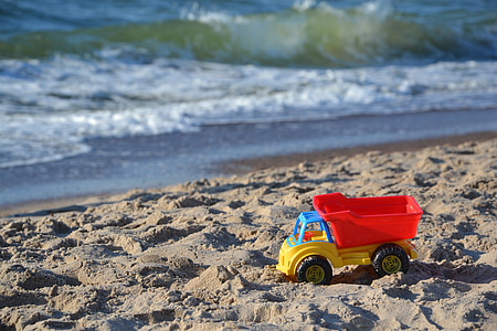 red and yellow dump truck toy on seashore thumbnail
