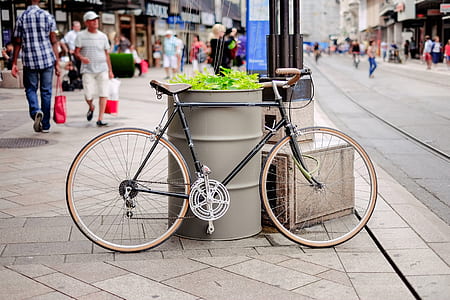 black bicycle parked beside gray metal drum thumbnail