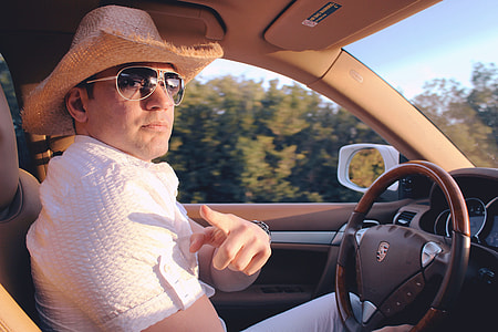 man wearing brown hat and white short sleeve Dress Shirt riding in car thumbnail