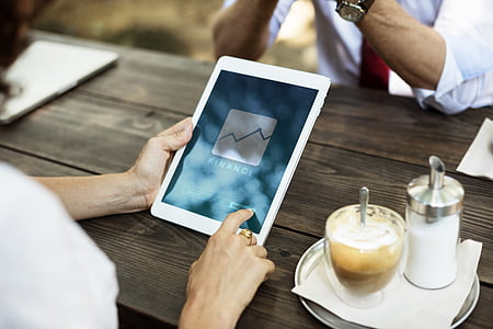 person holding of white tablet computer on brown wooden table thumbnail