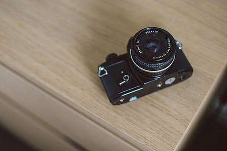 black point-and-shoot camera on brown wooden surface thumbnail