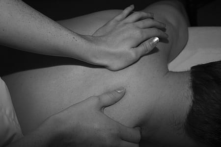 person touching back of person lying on surface thumbnail