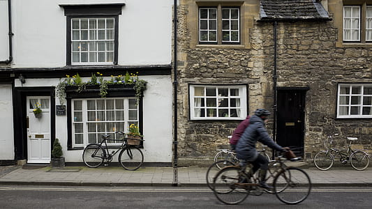 two man riding bicycle crossing beside houses thumbnail