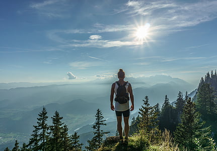 man in white tank top with black shorts top on hill under white clouds thumbnail