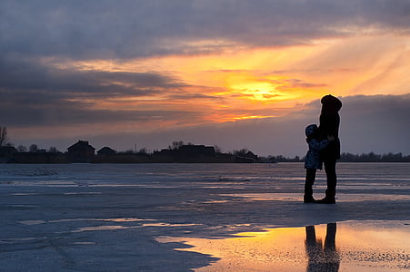 adult and toddler on seashore during golden hour thumbnail