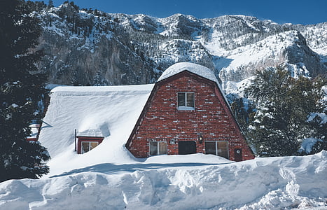 brown brick house surrounded by snow near mountain thumbnail