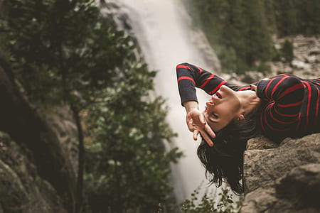 woman lying on rock near waterfalls thumbnail