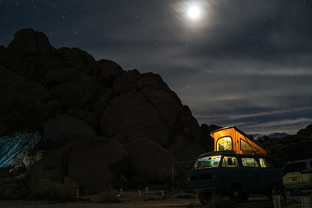 turned on lights of white bus in front of mountain under full moon thumbnail