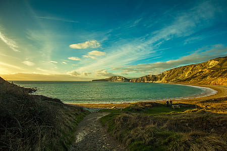brown mountain beside body of water during daytime thumbnail