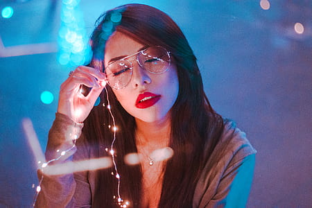 woman holding her eyeglasses with string lights thumbnail