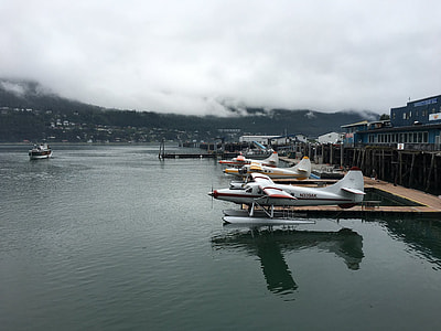 three parked white planes near body of water thumbnail