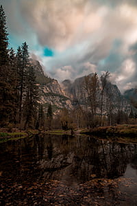 photo of body of water surrounded by trees near mountaing thumbnail