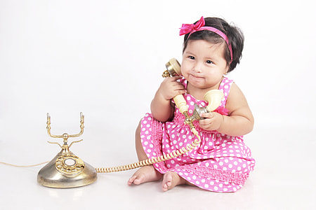 girl in pink polka dots dress holding cradle telephone thumbnail