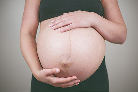closeup photography of pregnant woman holding her stomach wearing black crop top and black bottoms thumbnail
