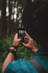 person in blue shirt and black hat holding black smartphone thumbnail