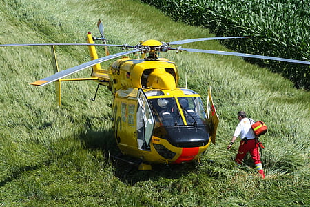 man walking near yellow and red helicopter during daytime thumbnail