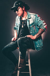 Man Wearing Denim Jacket While Sitting on Chair thumbnail