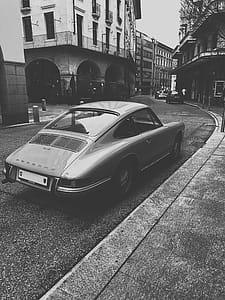 Grayscale Photo of Vintage Vehicle on Road Near Building thumbnail