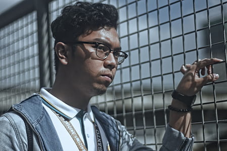 man wearing eyeglasses holding fence thumbnail