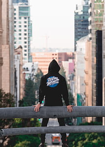man holding backwards the rail facing buildings and roads thumbnail