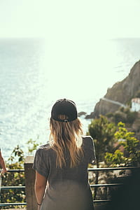 woman in gray top standing beside balustrades near body of water thumbnail