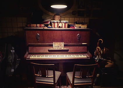 upright piano with two brown wooden chairs under pendant lamp thumbnail
