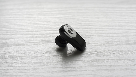 black Bluetooth earpiece on table thumbnail