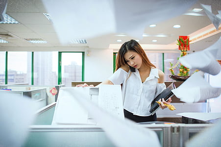 woman wearing white cold-shoulder button-up shirt holding black component and photocopier machine thumbnail
