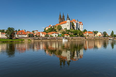 white and red concrete castle near body of water under blue sky during daytime thumbnail