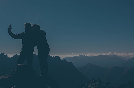 silhouette of couple taking picture on top of mountain thumbnail